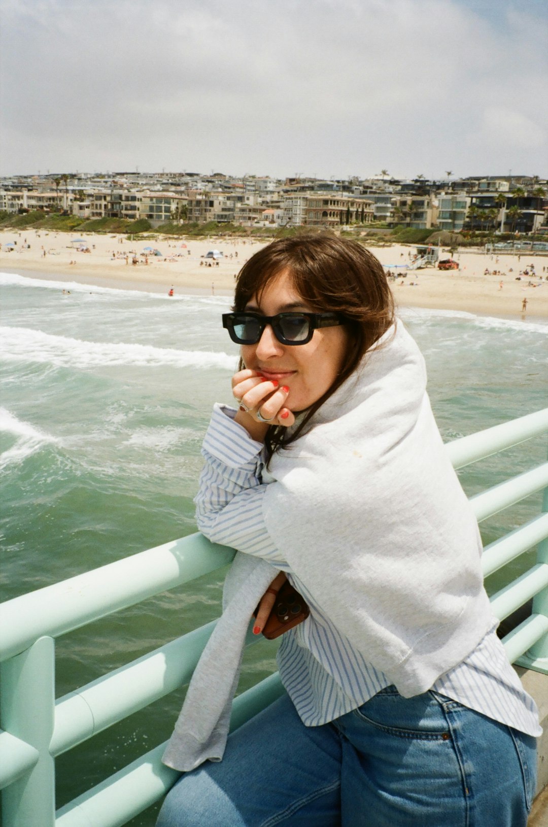Woman on pier overlooking beach and ocean.